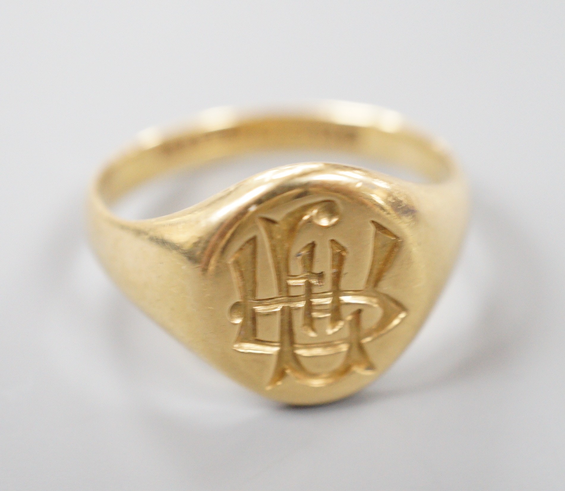A George V 18ct gold oval signet ring, with intaglio monogram and engraved inscription, size S/T, 8.1 grams.
